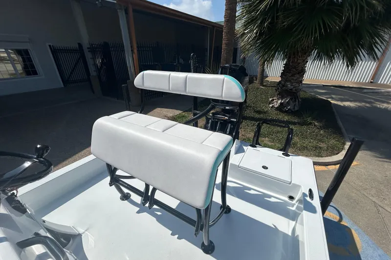 Slide: The Image of 2026 Shallow Sport 18 Sport boat with cushioned seating, parked outdoors near palm tree. - 13
