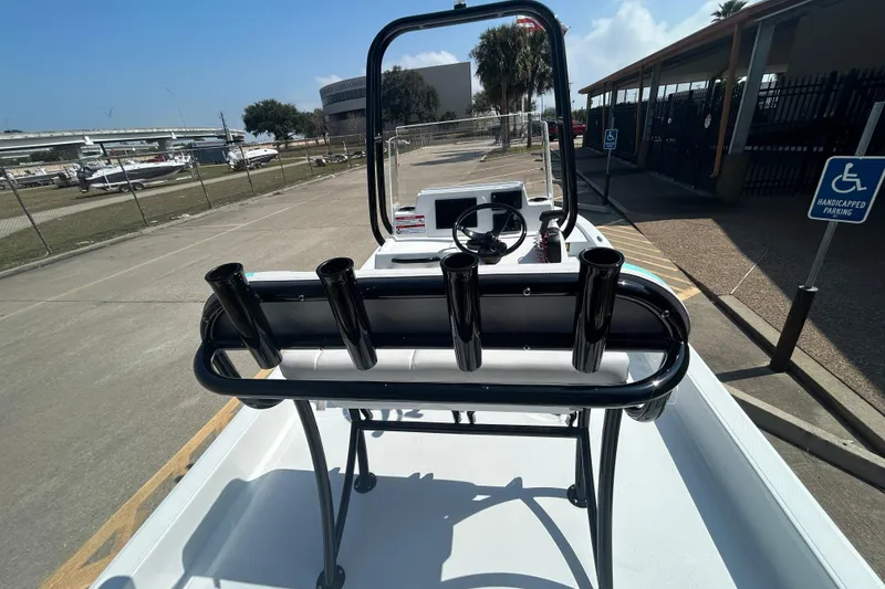 Slide: The Image of 2026 Shallow Sport 18 Sport boat with rod holders, parked near a marina. - 9