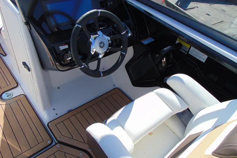 Slide: The Image of 2022 Yamaha Boats 212SE cockpit with steering wheel and white seating. - 10