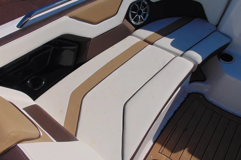 Slide: The Image of 2022 Yamaha Boats 212SE interior seating with brown and white upholstery, featuring a speaker and cup holder. - 16