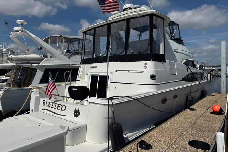 Slide: The Image of 2004 Carver 444 Cockpit Motor Yacht docked, featuring "Blessed" name and American flag. - 1
