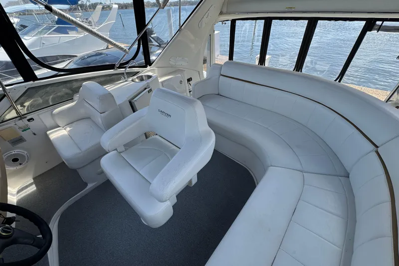 Slide: The Image of 2004 Carver 444 Cockpit Motor Yacht interior with white seating and helm, overlooking water. - 15