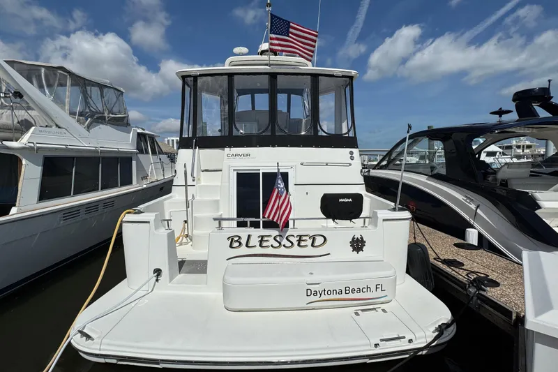 Slide: The Image of 2004 Carver 444 Cockpit Motor Yacht docked in Daytona Beach, FL, with American flags. - 2