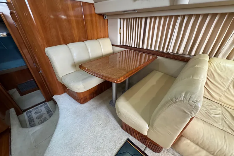 Slide: The Image of 2004 Carver 444 Cockpit Motor Yacht interior with beige seating and wooden table. - 28