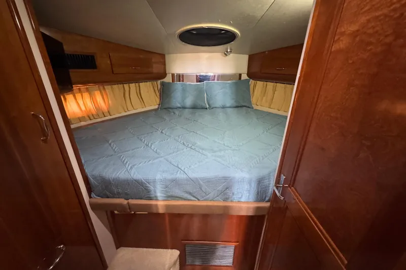 Slide: The Image of 2004 Carver 444 Cockpit Motor Yacht bedroom with cozy bed and wooden cabinetry. - 31