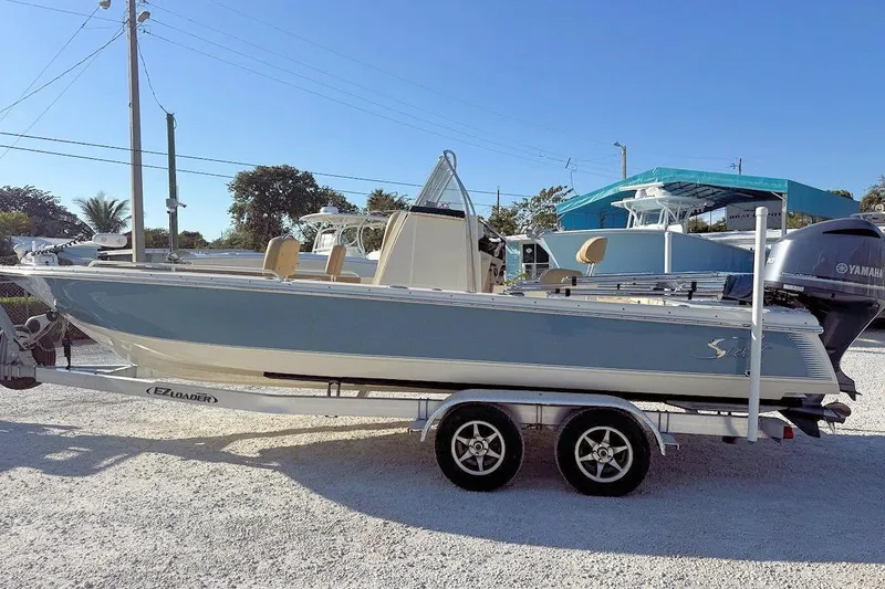 Slide: The Image of 2016 Scout 251 XS boat on trailer, parked outdoors under clear blue sky. - 4