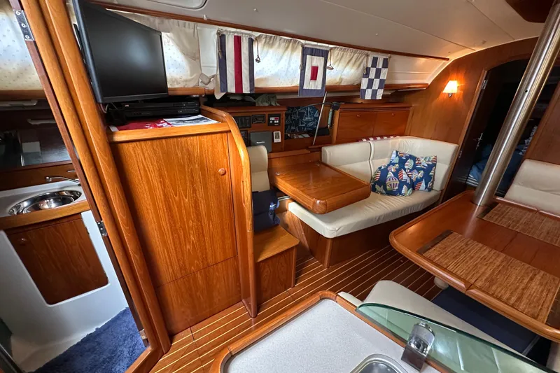 Slide: The Image of Interior of 2004 Jeanneau Sun Odyssey 35 sailboat with wood finish and cozy seating area. - 21