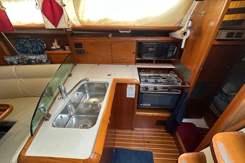 Slide: The Image of Interior of 2004 Jeanneau Sun Odyssey 35 yacht, featuring kitchen with sink, stove, and microwave. - 22