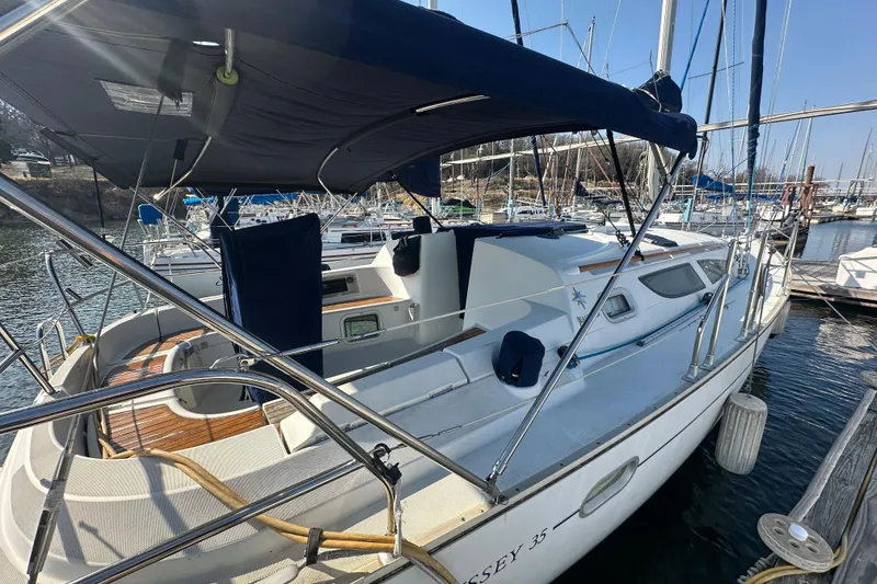 Slide: The Image of 2004 Jeanneau Sun Odyssey 35 sailboat docked at marina, featuring spacious deck and canopy. - 7