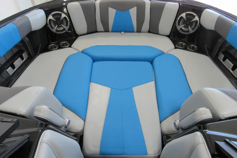 Slide: The Image of 2021 Malibu Wakesetter 24 MXZ interior with blue and gray seating, cup holders, and speakers. - 11