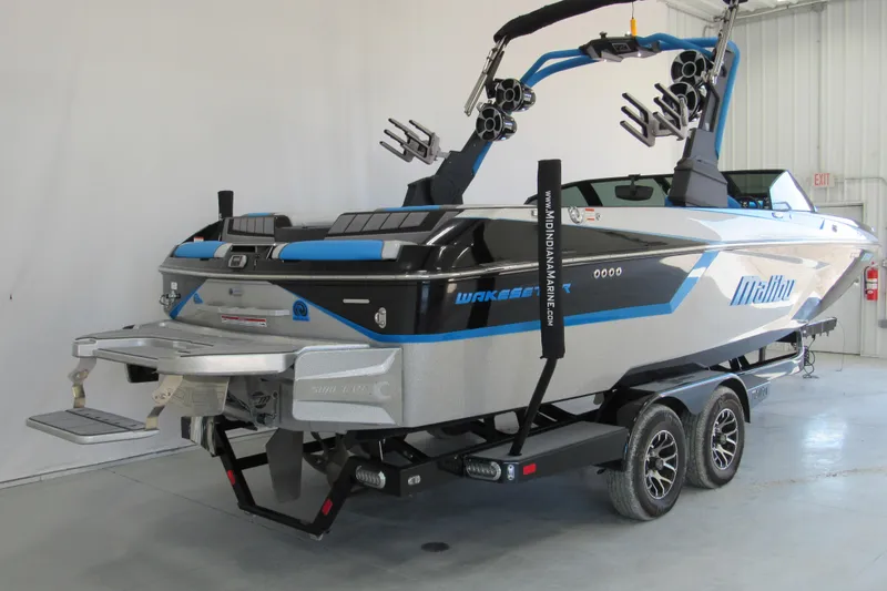 Slide: The Image of 2021 Malibu Wakesetter 24 MXZ boat in showroom, featuring sleek design and advanced wakeboarding features. - 2
