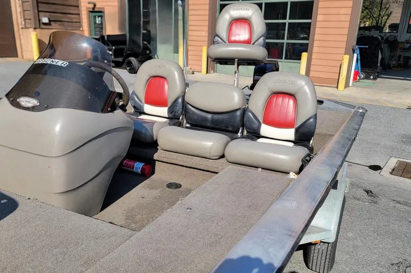 Slide: The Image of 2003 Tracker Pro Team 175 boat interior with red and gray seating, parked outdoors. - 7