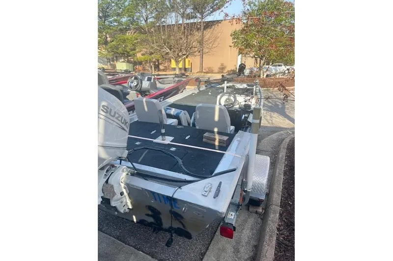 Slide: The Image of 1985 Grumman Outlaw boat with Suzuki motor, parked outdoors. - 2