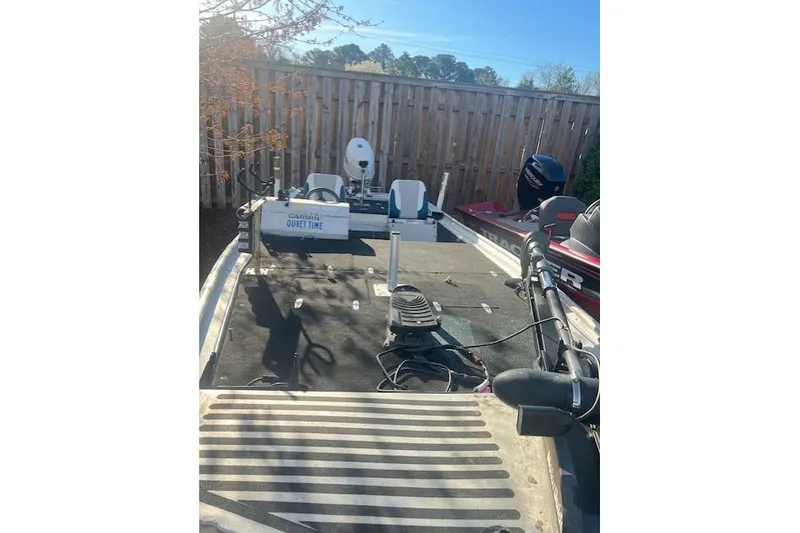 Slide: The Image of 1985 Grumman Outlaw boat with fishing equipment and motors, parked outdoors. - 3