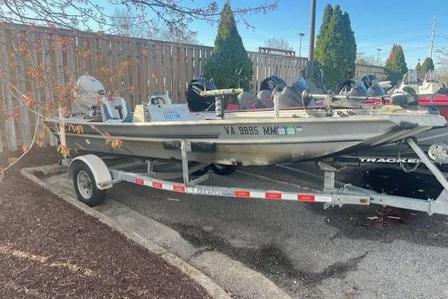 Slide: The Image of 1985 Grumman Outlaw boat on trailer, parked outdoors near wooden fence. - 8