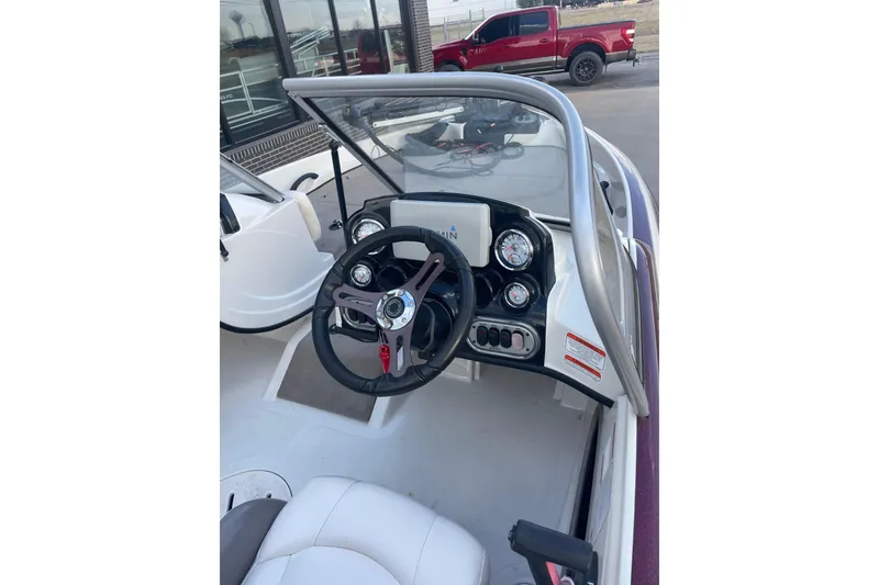 Slide: The Image of 2016 Nitro Z-7 Sport boat dashboard with steering wheel and gauges, parked near a red truck. - 3