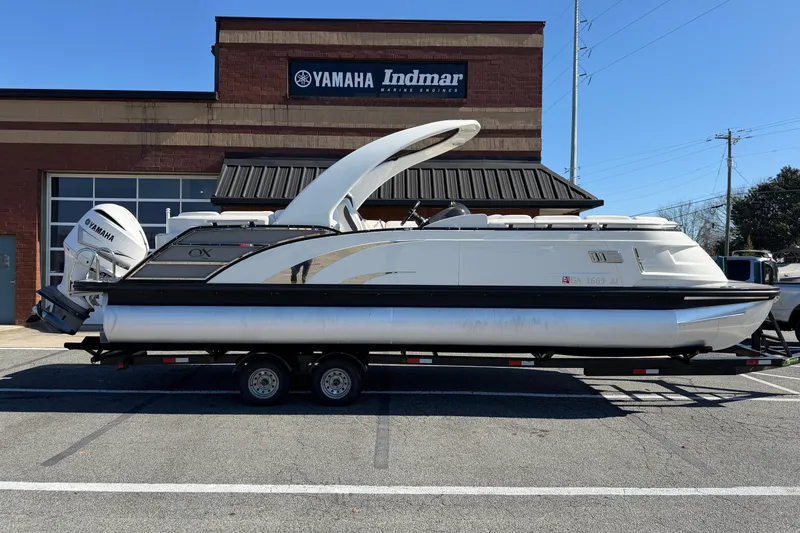 The Image of 2021 Bennington QX 25 QXFBA pontoon boat on trailer, parked outside Yamaha dealership. - 0