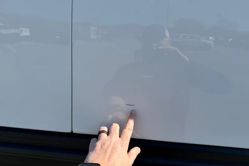 Slide: The Image of Hand pointing at a small dent on a 2021 Bennington QX 25 QXFBA boat. - 3