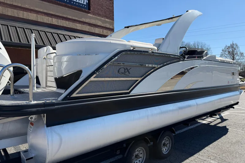 Slide: The Image of 2021 Bennington QX 25 QXFBA pontoon boat on trailer, sleek design, outdoor setting. - 5