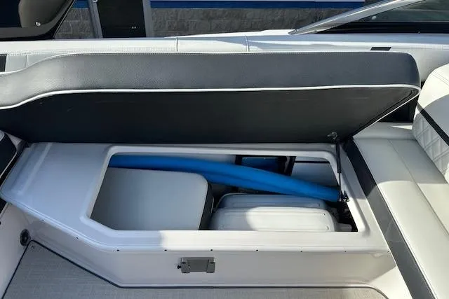 Slide: The Image of 2023 Regal 2800 Bowrider storage compartment with blue pool noodle and cooler. - 23