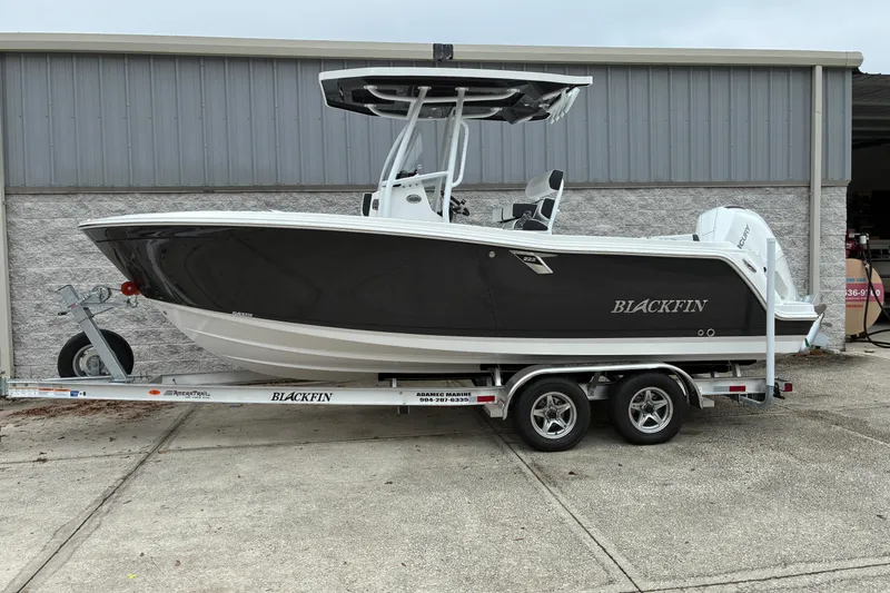 Slide: The Image of 2026 Blackfin 222 CC boat on trailer, parked outside a building. - 2