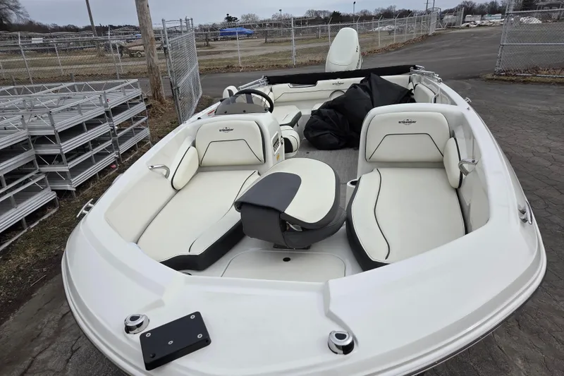 Slide: The Image of 2020 Stingray 182 SC boat with white seating, parked outdoors near a fence. - 3