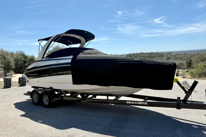 Slide: The Image of 2008 Crownline 260 LS boat on trailer with cover, parked outdoors under clear sky. - 17