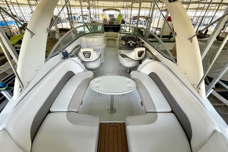 Slide: The Image of 2008 Crownline 260 LS boat interior with white seating and table, docked in a marina. - 20