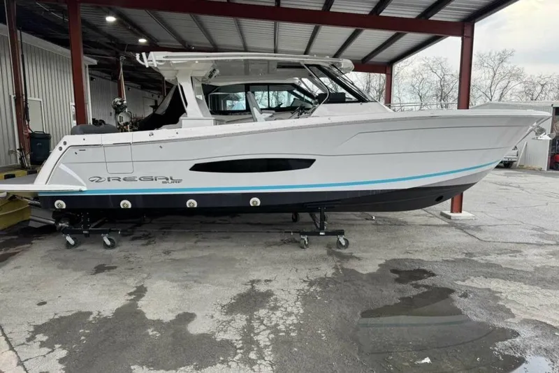 The Image of 2026 Regal 38 Surf boat in storage, side view under a metal roof. - 1