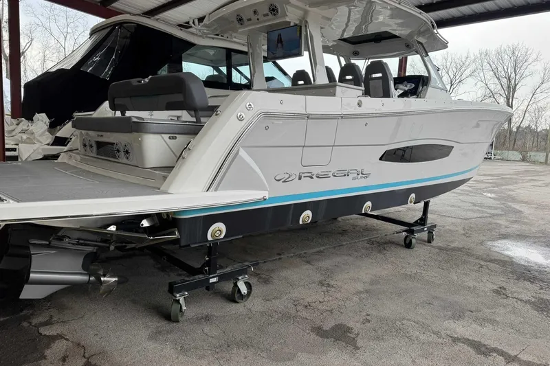 Slide: The Image of 2026 Regal 38 Surf boat on trailer, under a covered area, showcasing sleek design. - 4