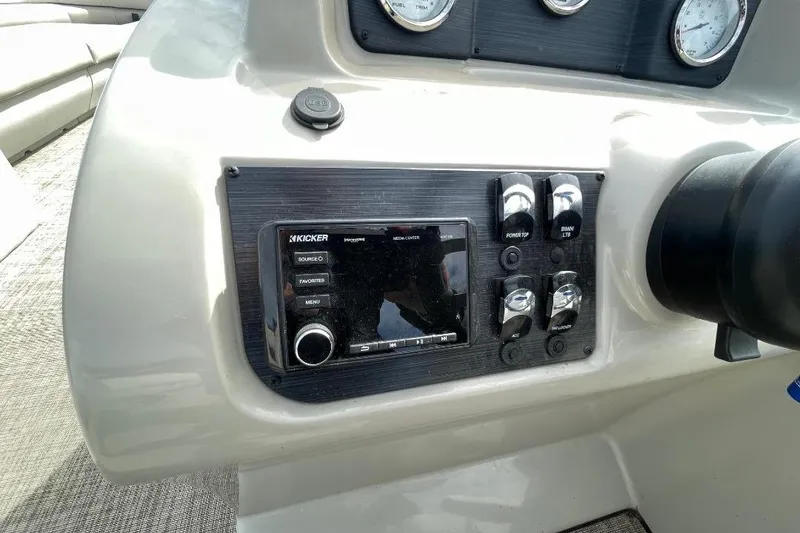 Slide: The Image of Control panel of 2023 Cypress Cay Seabreeze 252 boat with audio system and switches. - 12