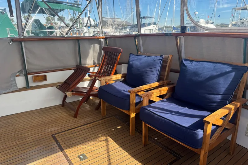 Slide: The Image of 1966 Grand Banks 32 Sedan interior with wooden chairs and blue cushions on deck. - 14