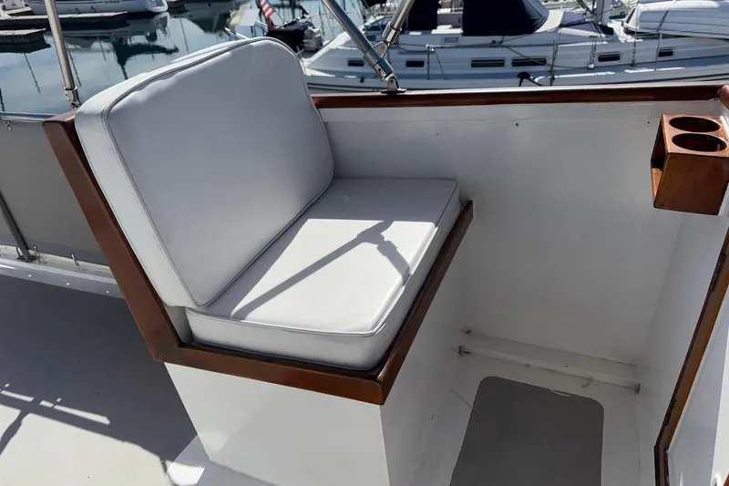 Slide: The Image of White cushioned seat on 1966 Grand Banks 32 Sedan boat with wooden cup holder. - 30