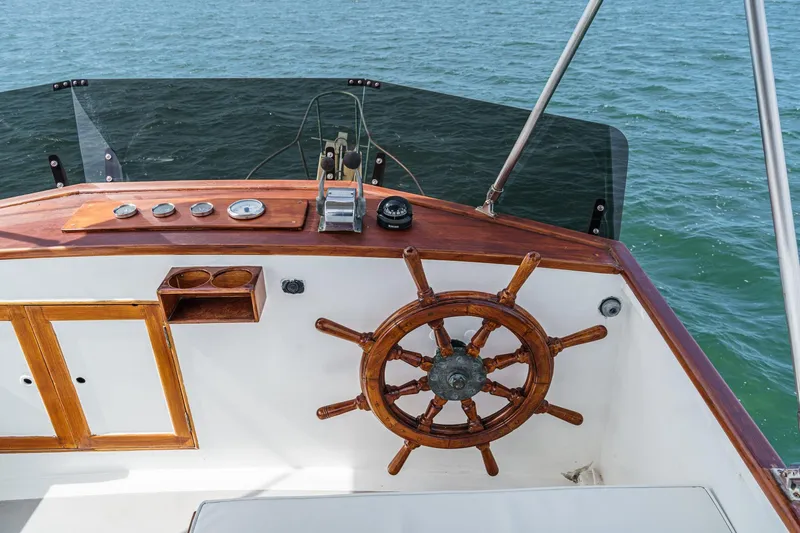 Slide: The Image of 1966 Grand Banks 32 Sedan helm with wooden wheel and ocean backdrop. - 48
