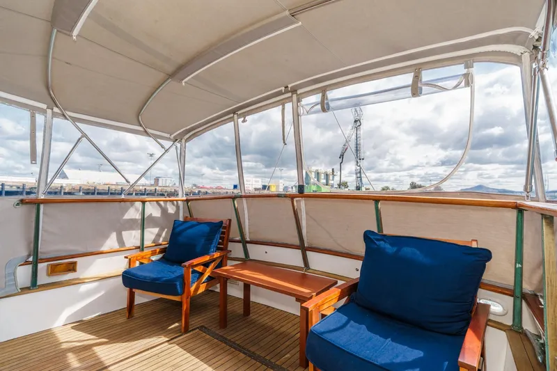 Slide: The Image of 1966 Grand Banks 32 Sedan interior with blue-cushioned chairs and wooden accents. - 49