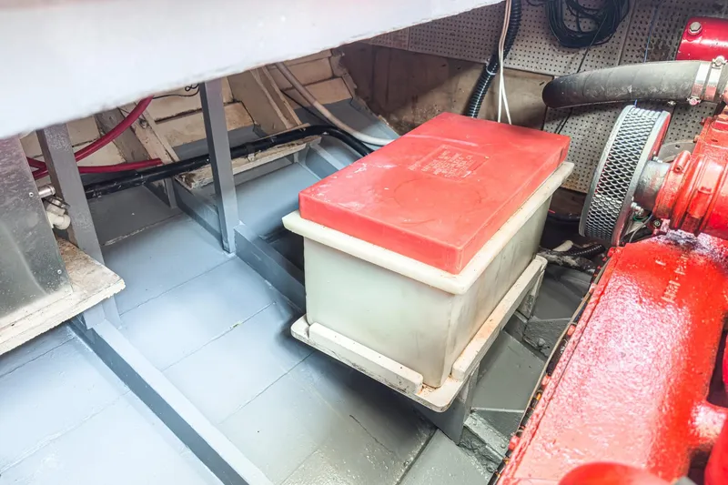 Slide: The Image of Engine compartment of a 1966 Grand Banks 32 Sedan with battery and red engine components. - 53