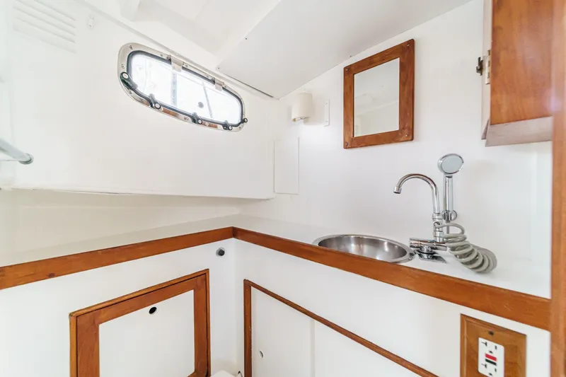 Slide: The Image of 1966 Grand Banks 32 Sedan interior with sink, mirror, and wooden accents. - 62