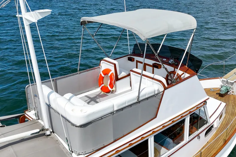 Slide: The Image of 1966 Grand Banks 32 Sedan boat with upper deck seating and life preserver on blue water. - 68