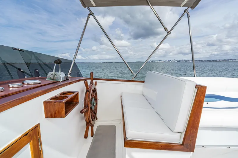 Slide: The Image of 1966 Grand Banks 32 Sedan helm with wooden wheel, white seating, and ocean view. - 69