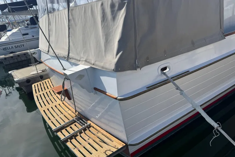 Slide: The Image of 1966 Grand Banks 32 Sedan boat docked, featuring wooden deck and protective cover. - 7