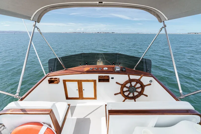 Slide: The Image of 1966 Grand Banks 32 Sedan helm with wooden wheel, overlooking calm ocean waters. - 72