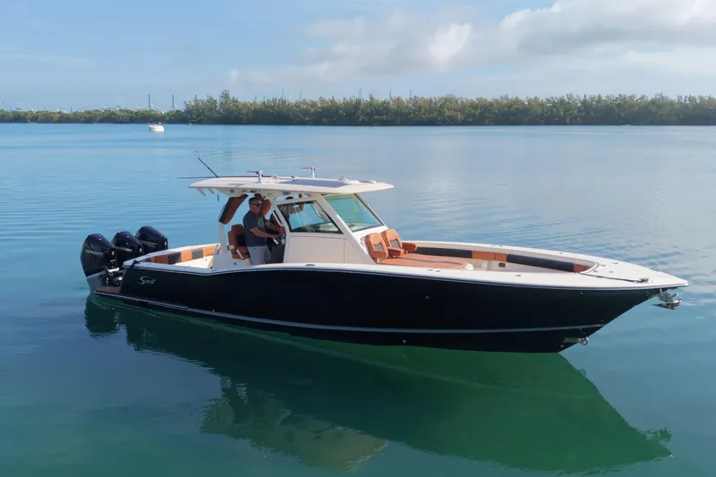 Slide: The Image of 2019 Scout 355 LXF boat on calm water, featuring sleek design and triple outboard engines. - 2