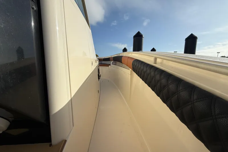 Slide: The Image of 2019 Scout 355 LXF boat deck with cushioned railing under clear sky. - 26