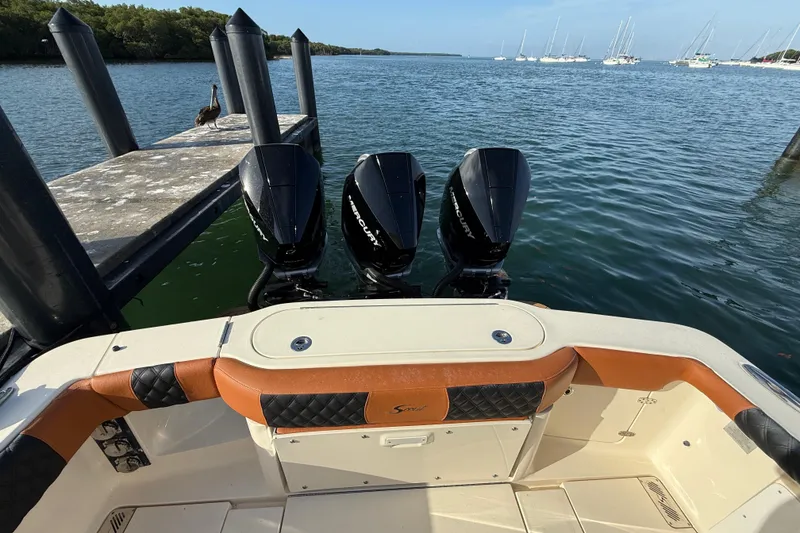 Slide: The Image of 2019 Scout 355 LXF boat with triple Mercury engines docked by the water. - 27