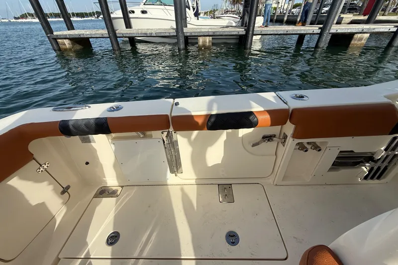 Slide: The Image of 2019 Scout 355 LXF boat interior near dock, featuring seating and water view. - 32
