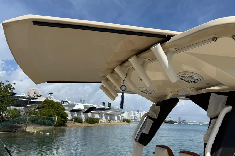 Slide: The Image of 2019 Scout 355 LXF boat with rod holders and speakers, docked near a marina. - 41