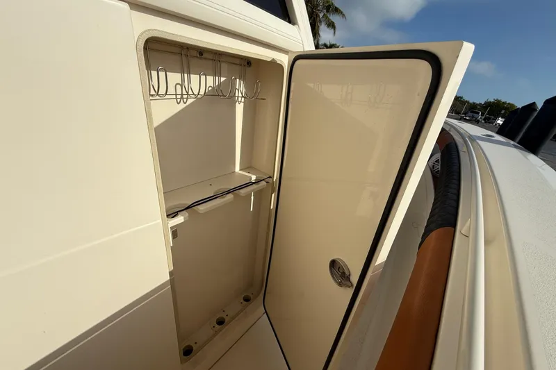 Slide: The Image of 2019 Scout 355 LXF boat storage compartment with open door, showcasing interior hooks. - 55