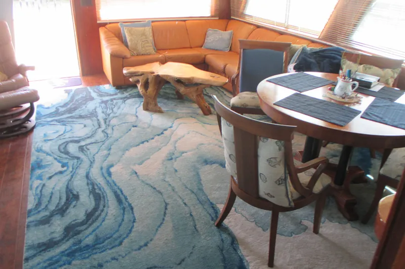 Slide: The Image of Interior of 1981 Hatteras 61 Motor Yacht with blue abstract rug and wooden furniture. - 14