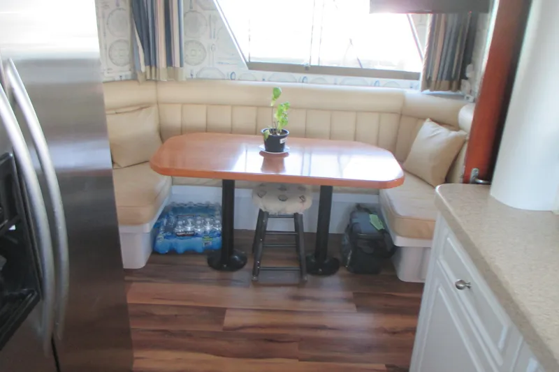 Slide: The Image of Cozy dining area in 1981 Hatteras 61 Motor Yacht with wooden table and cushioned seating. - 18