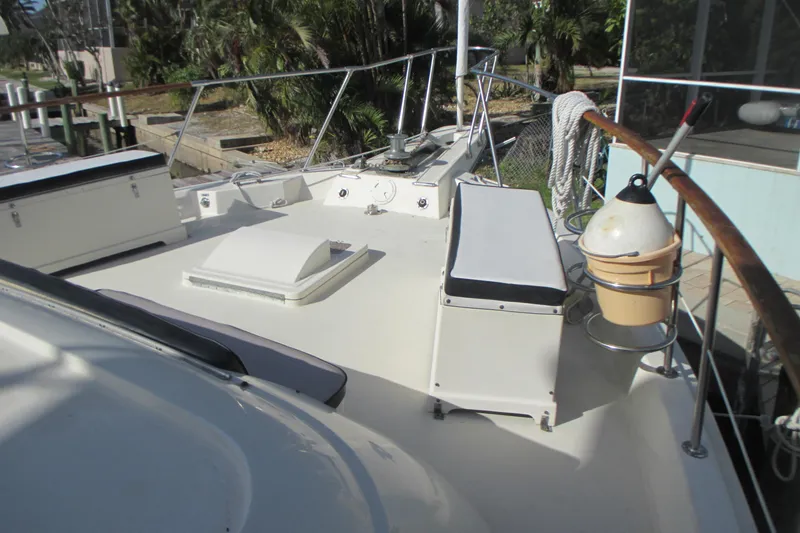 Slide: The Image of 1981 Hatteras 61 Motor Yacht deck with seating and railing, docked near greenery. - 6